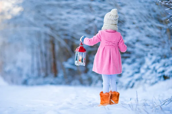 Adorable little girl wearing warm coat outdoors on Christmas day holding flashlight