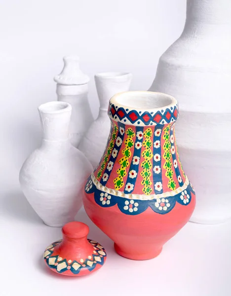 Egyptian decorated colorful pottery vase on background of white vases