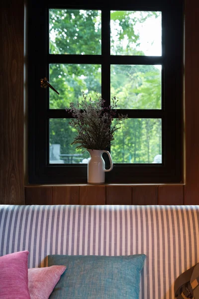Pillow, sofa and flower beside window