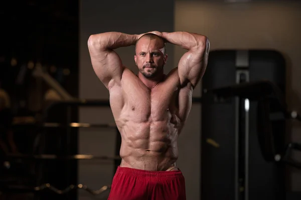 Muscular Man Flexing Muscles In Gym