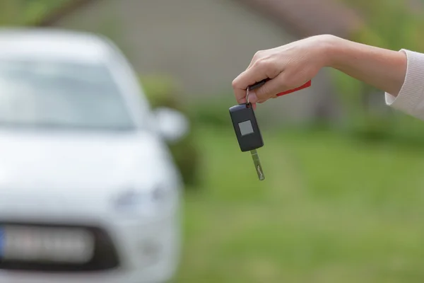 Women holding car keys with new car in background