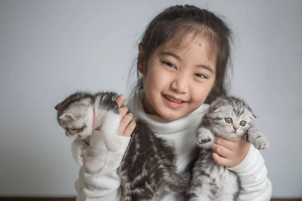Happy little Asian girl hugging lovely scottish fold kitten