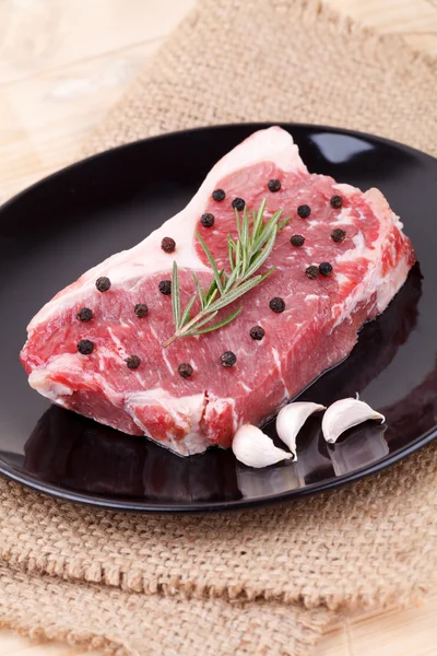 Raw red sirloin steak with rosemary, garlic , pepper