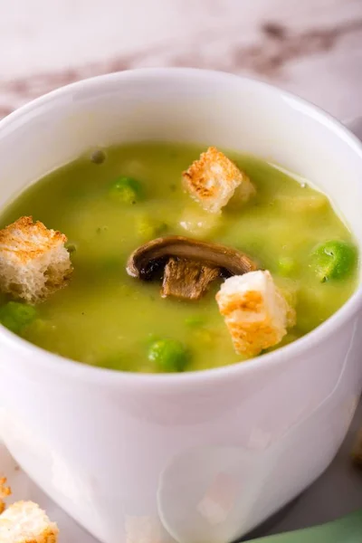 Detail of split pea soup in white cup and croutons