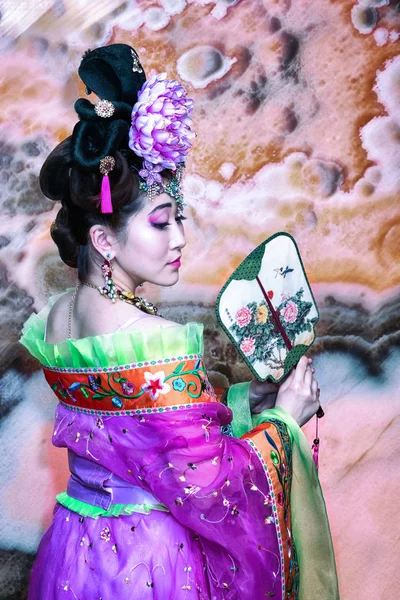 Chinese girl in traditional clothes with fan, rear turn view