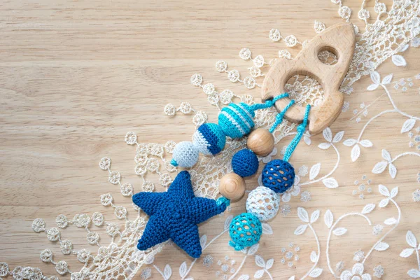 Wooden spaceship toy and knitted beads on a lace and wood with copy space. Necklace made from knitted beads and toys for the baby sitting in a sling. Space travel concept.