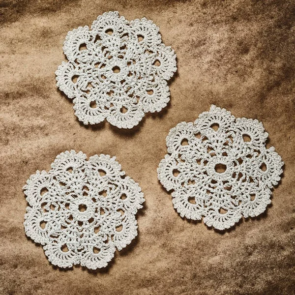 Three crochet pattern coasters on  dark paper background, square