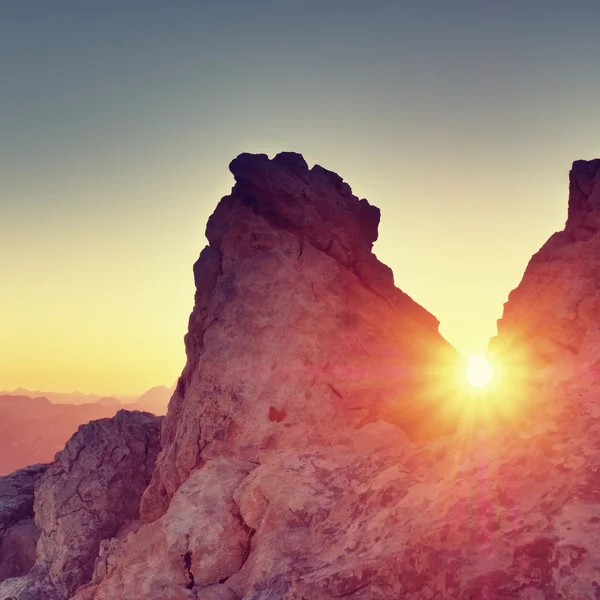 Morning sun between shar rocks,  Alpine  cliff above valley. Daybreak Sun