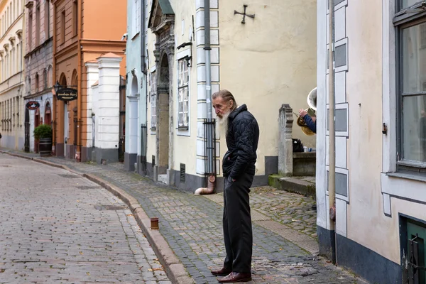 Poor old man at central street of old town in Riga, Latvia