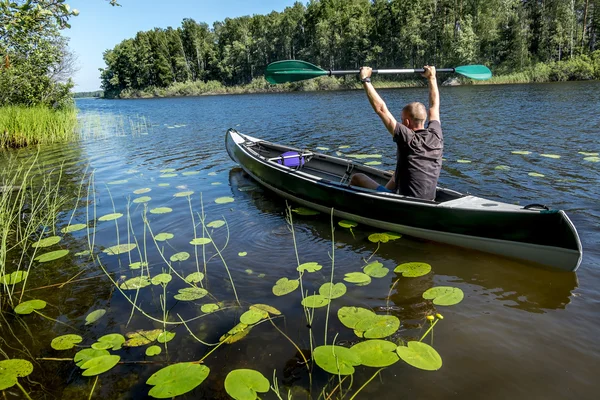 A man swims on a kayak on the lake in summer  day