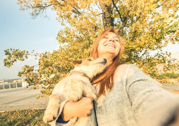 Young redhead woman taking surprised selfie outdoors with cute dog on spontaneous face expression - Friendship concept between people and animals - Warm sunny afternoon color tones in autumn day