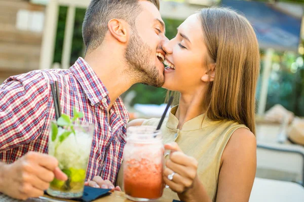 Handsome man kissing young woman at fashion cocktail bar - Happy couple of lovers at beginning of love story - Feelings concept with boyfriend and girlfriend on warm filtered look - Focus on the lips