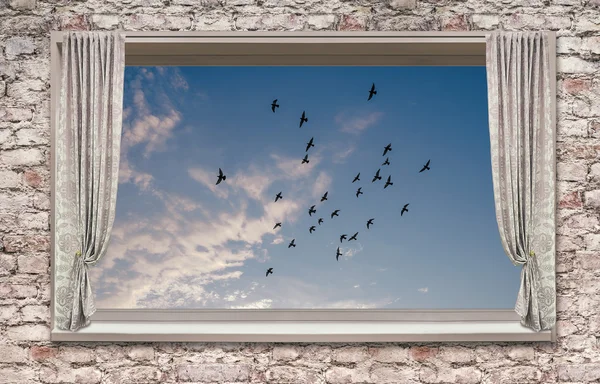 Lightweight, light gray curtains adorn the window overlooking the blue sky, light clouds, and flying birds.