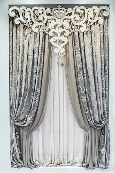 The modern interior design. Combined double curtains, light tulle and a carved pelmet