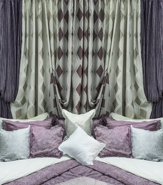 The stylish design of the bedroom. Contrasting curtains with geometric pattern and the bed linen are matched in the interior