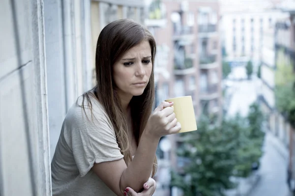 Young sad beautiful woman suffering depression looking worried and wasted on home balcony