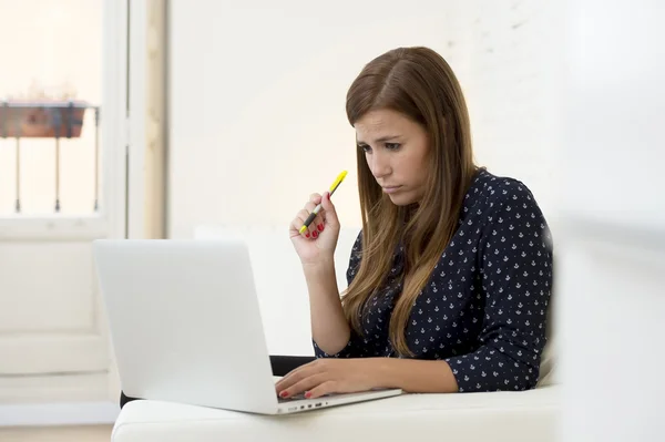 Woman using laptop computer networking or online internet shopping at home couch