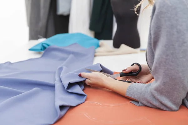 Side view of woman cutting blue material