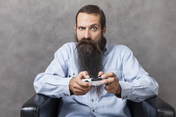 Man with long beard is playing a video game is surprised by the plot twist. Concept of video game as art