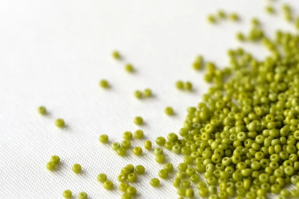 Scattered seed beads of olive color on the textile background