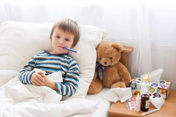 Sick child boy lying in bed with a fever, resting