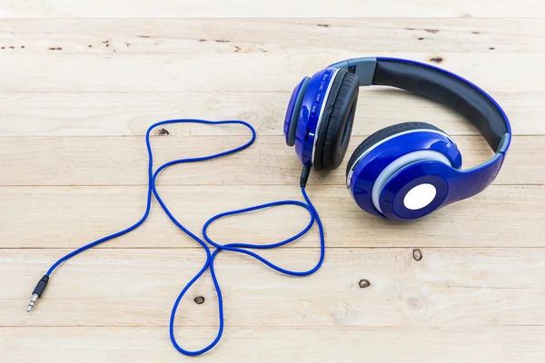 Blue headphones on wood desk.