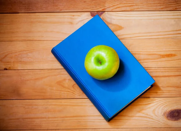 Apple and book on wooden background. Top view