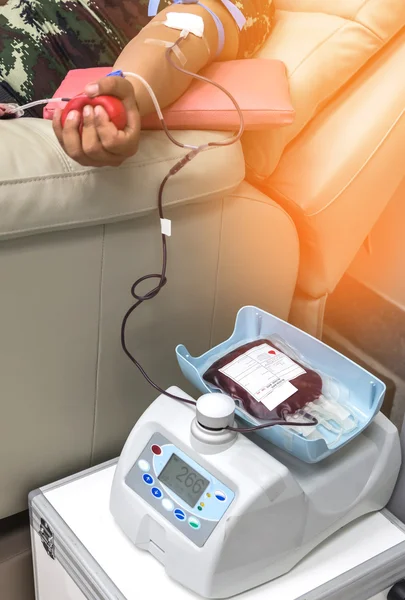 Blood donor at donation with red bouncy ball holding in hand during the transfusion