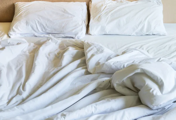 Messy white bed sheets and white pillows