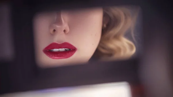 Beautiful sensual caucasian woman with exotic appearance with curled blonde hairstyle and red lips, looking sideways on a rearview mirror in the car. close up of lips