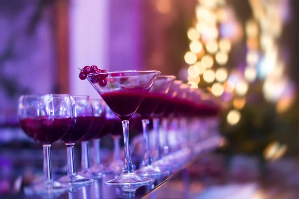 Beautiful row line of different colored alcohol cocktails with mint on a open air party, martini, vodka with bubbles,and others on decorated catering bouquet wedding table on open air event
