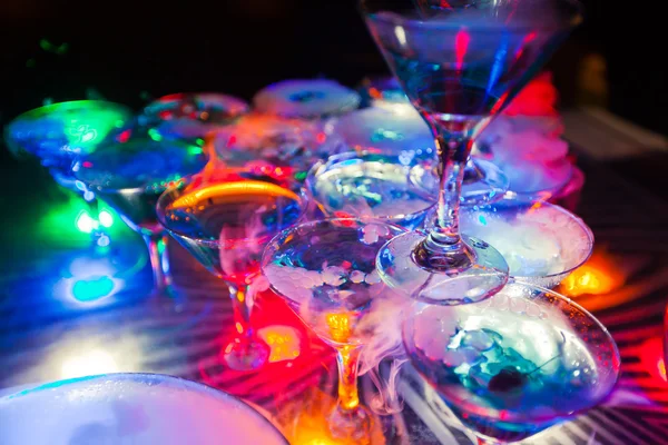 Beautiful row line of different colored alcohol cocktails with mint on a open air party, martini, vodka with bubbles,and others on decorated catering bouquet wedding table on open air event