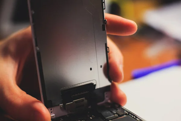 A close-up process of disassemble and dismantle modern mobile phone smartphone with broken shattered display glass and changing details at home
