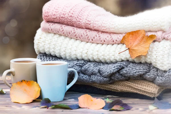 Knitted clothes coffee mugs on wood. Fall season mood icon.