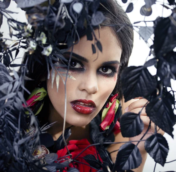 Pretty brunette woman with rose jewelry, black and red, bright make up kike a vampire closeup red lips