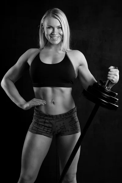Girl with a barbell on black background