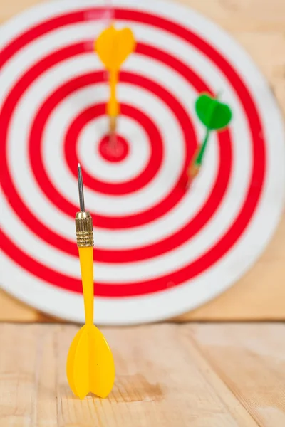 Dart arrow and dartboard on wood background