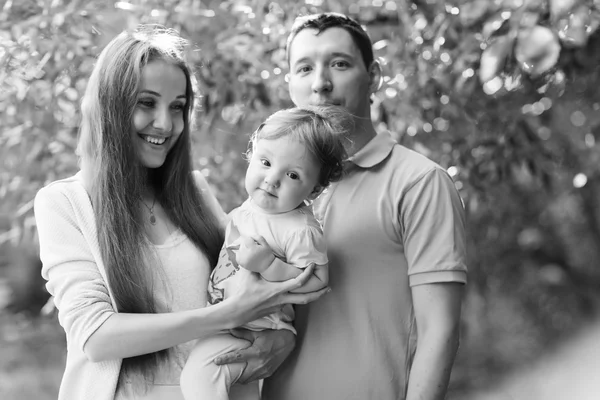 Happy couple with daughter in park, black - white photo