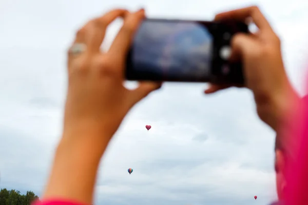 Hands taking photo of hot air balloon on phone