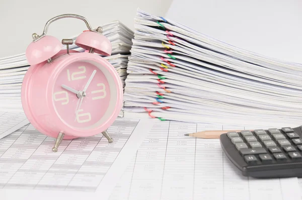 Brown pencil and old pink alarm clock on finance account