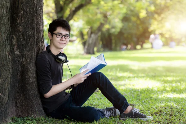 Asian young handsome man student reading book in nature. One stu