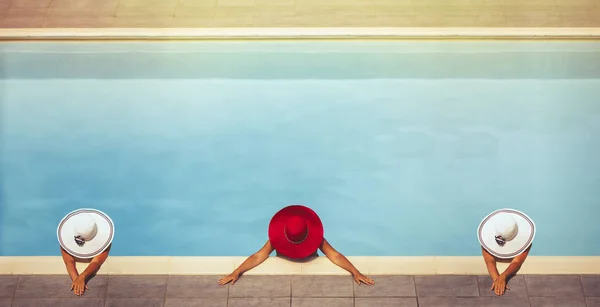 Three young females in hats in the pool
