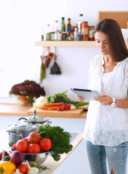 Young woman using a tablet computer to cook in her kitchen