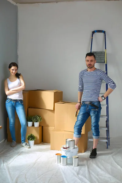 Portrait happy smiling young couple painting interior wall of new house