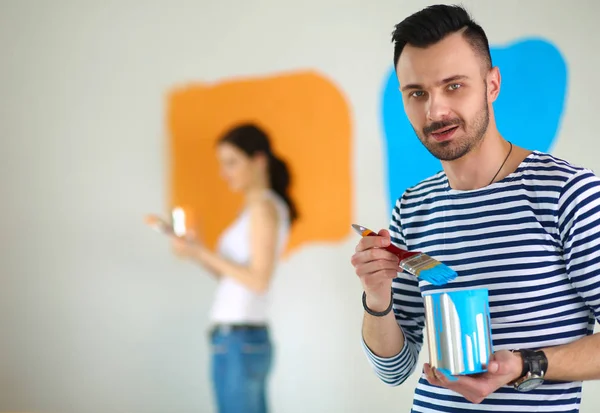 Portrait happy smiling young couple painting interior wall of new house