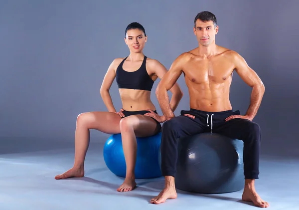 Two smiling people with fitness ball in the gym
