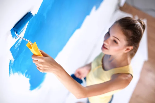 Beautiful young woman doing wall painting , standing