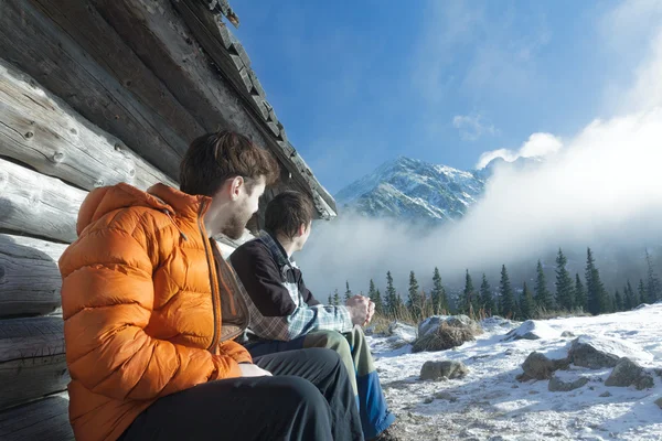 Friends resting on wood bench in winter mountains outdoors