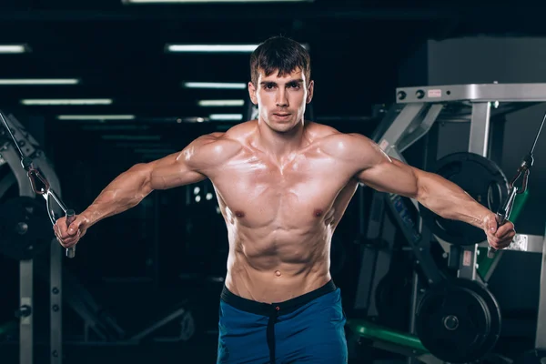 Handsome bodybuilder works out pushing up excercise in gym