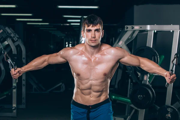 Handsome bodybuilder works out pushing up excercise in gym